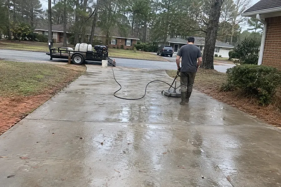 Worker surface cleaning a concrete driveway in a Greenville SC neighborhood